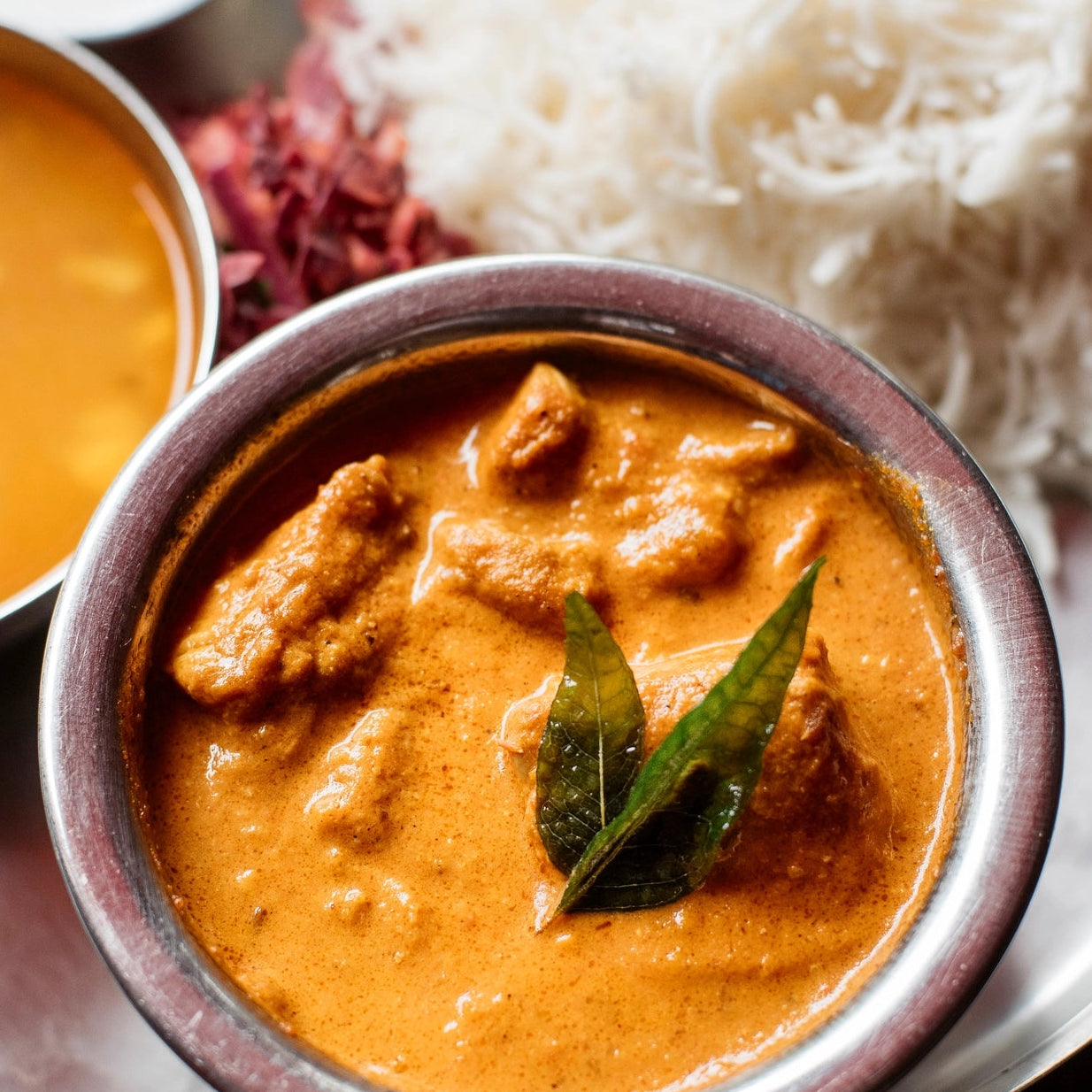 Indonesian traditional dish with curry, rice, and sambal on a metal plate.