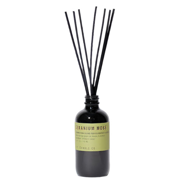 A reed diffuser with black dyed rattan reeds inserted into a smoke grey bottle, labeled 'GERANIUM MOSS'.