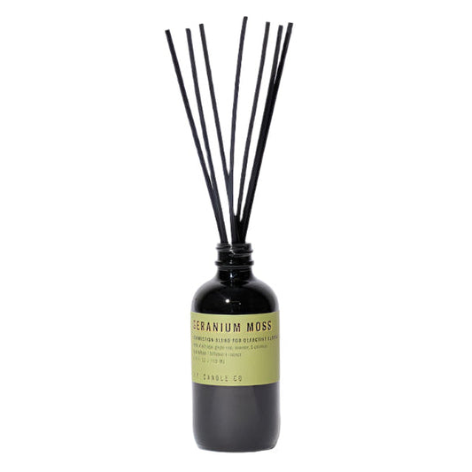 A reed diffuser with black dyed rattan reeds inserted into a smoke grey bottle, labeled 'GERANIUM MOSS'.