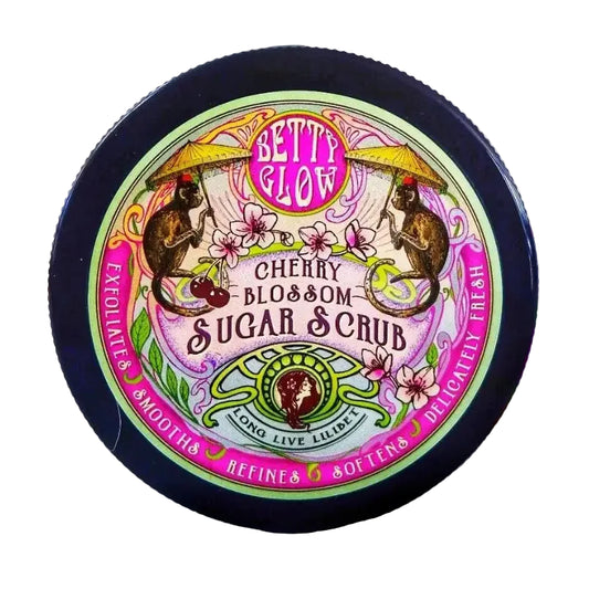 Jar of Betty Glow Cherry Blossom Sugar Scrub with floral background