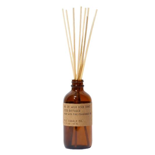 A 3.5 oz amber-colored reed diffuser with a label and a group of dried rattan reeds inserted at the top, set against a white background.