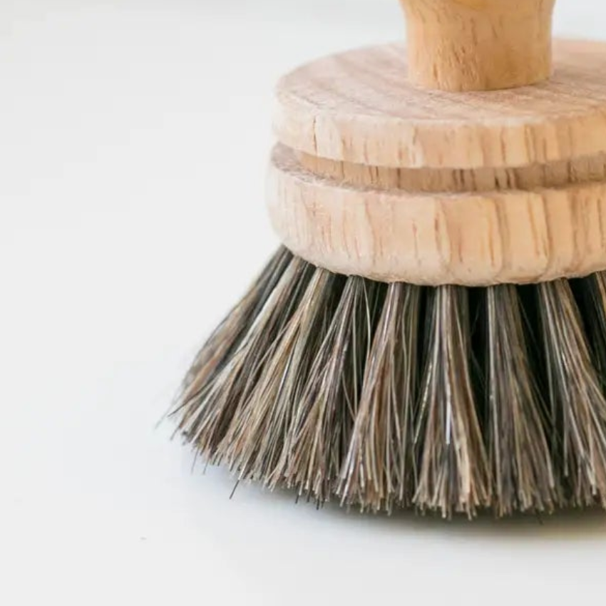 Dish brush with wooden handle and bristles on a light background