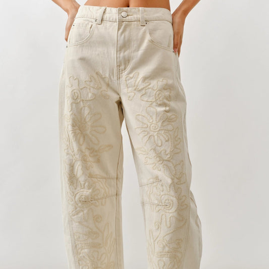 Person wearing beige embroidered pants on a white background