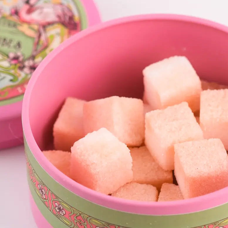 Pink container with sugar cubes and decorative lid on a white background