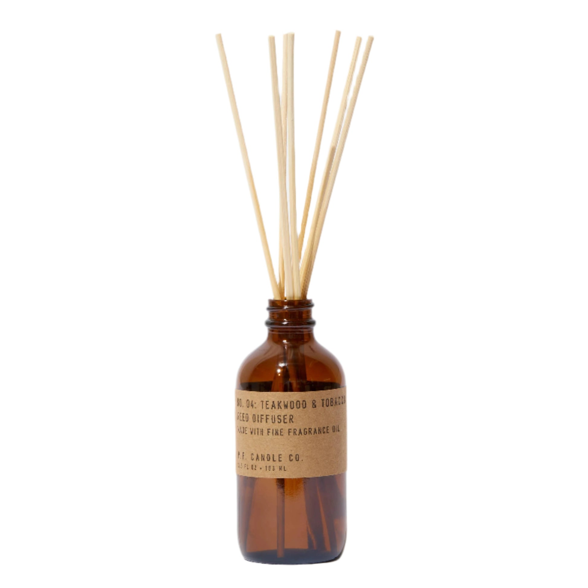 A clear glass reed diffuser with a amber-colored bottle and several light brown rattan reeds visible through the transparent bottom.
